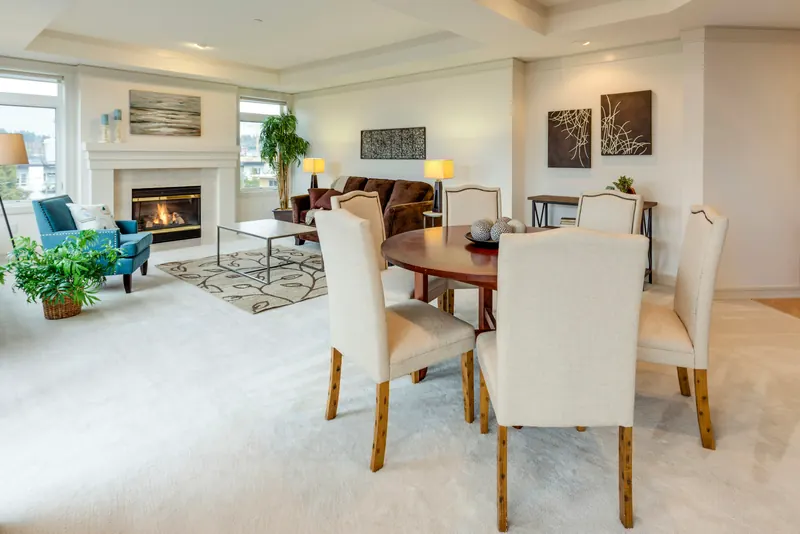 Reference photograph: upholstered dining chairs beside a cream living room and broad windows.