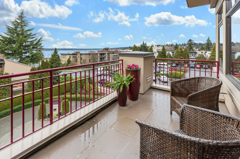 Reference photograph: two woven chairs on a railed balcony overlooking trees.