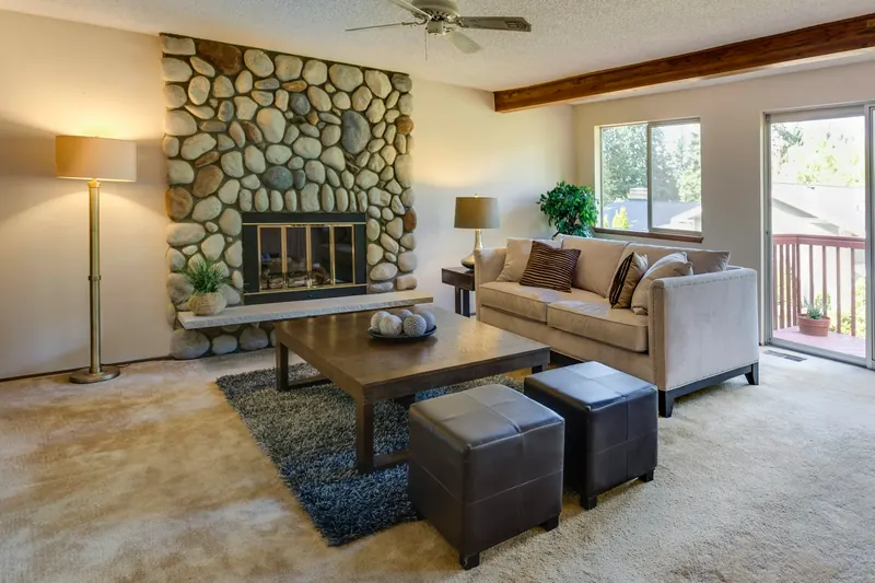 Reference photograph: a stone fireplace beside beige seating and glazed garden doors.