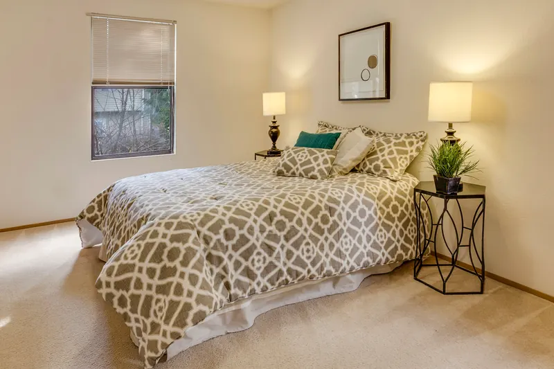 Reference photograph: a softly lit bedroom with patterned bedding and green cushions.