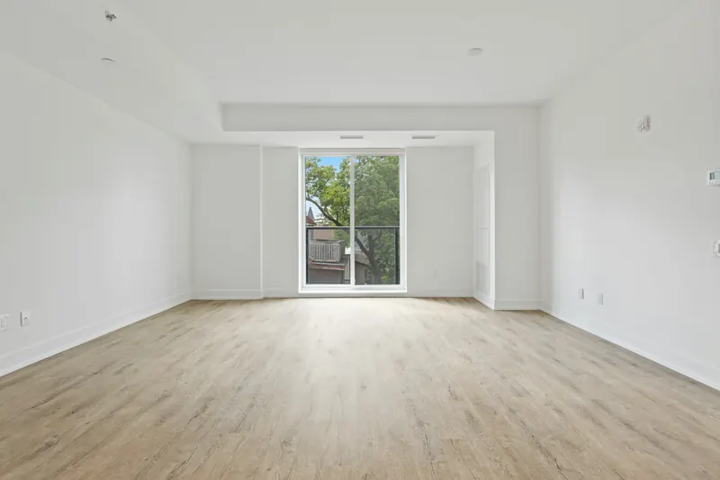 Reference photograph: an unfurnished open room with pale wood flooring and glazed doors.
