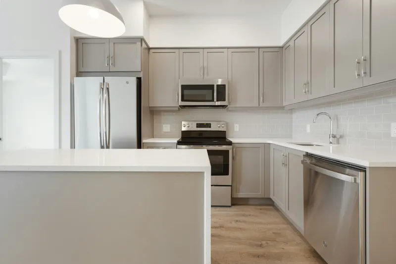 Reference photograph: grey kitchen units and a pale counter seen from the open room.