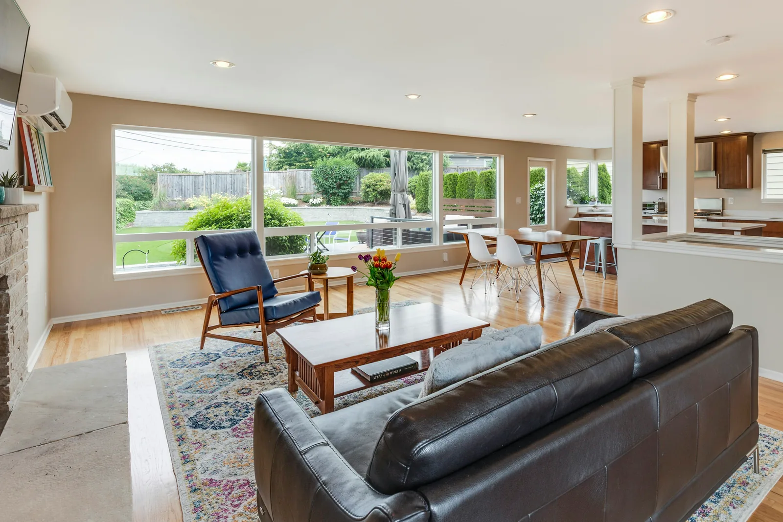 Reference photograph: a living room with wide garden windows, dark seating and a wood floor.