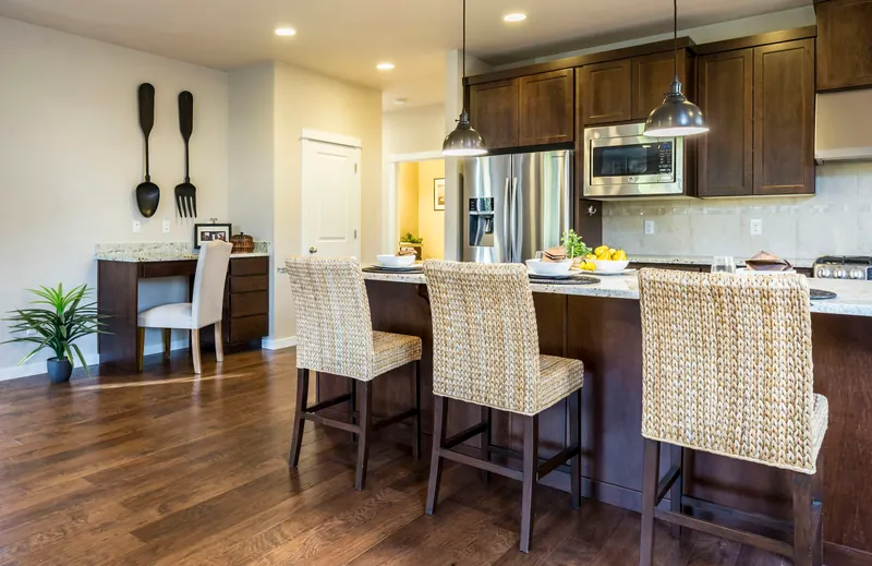 Reference photograph: a kitchen with dark wood cabinets, a pale island and woven bar stools.