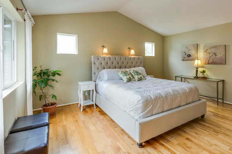 Reference photograph: a pale bedroom with an upholstered bed, wood floor and glazed doors.