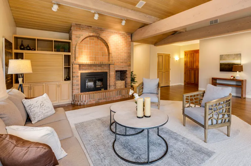 Reference photograph: a brick fireplace framed by pale armchairs and built-in shelving.