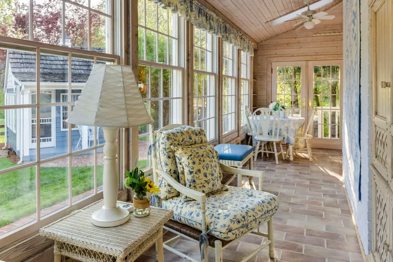 Reference photograph: a glazed sitting room with woven seating, wood boarding and a garden outlook.