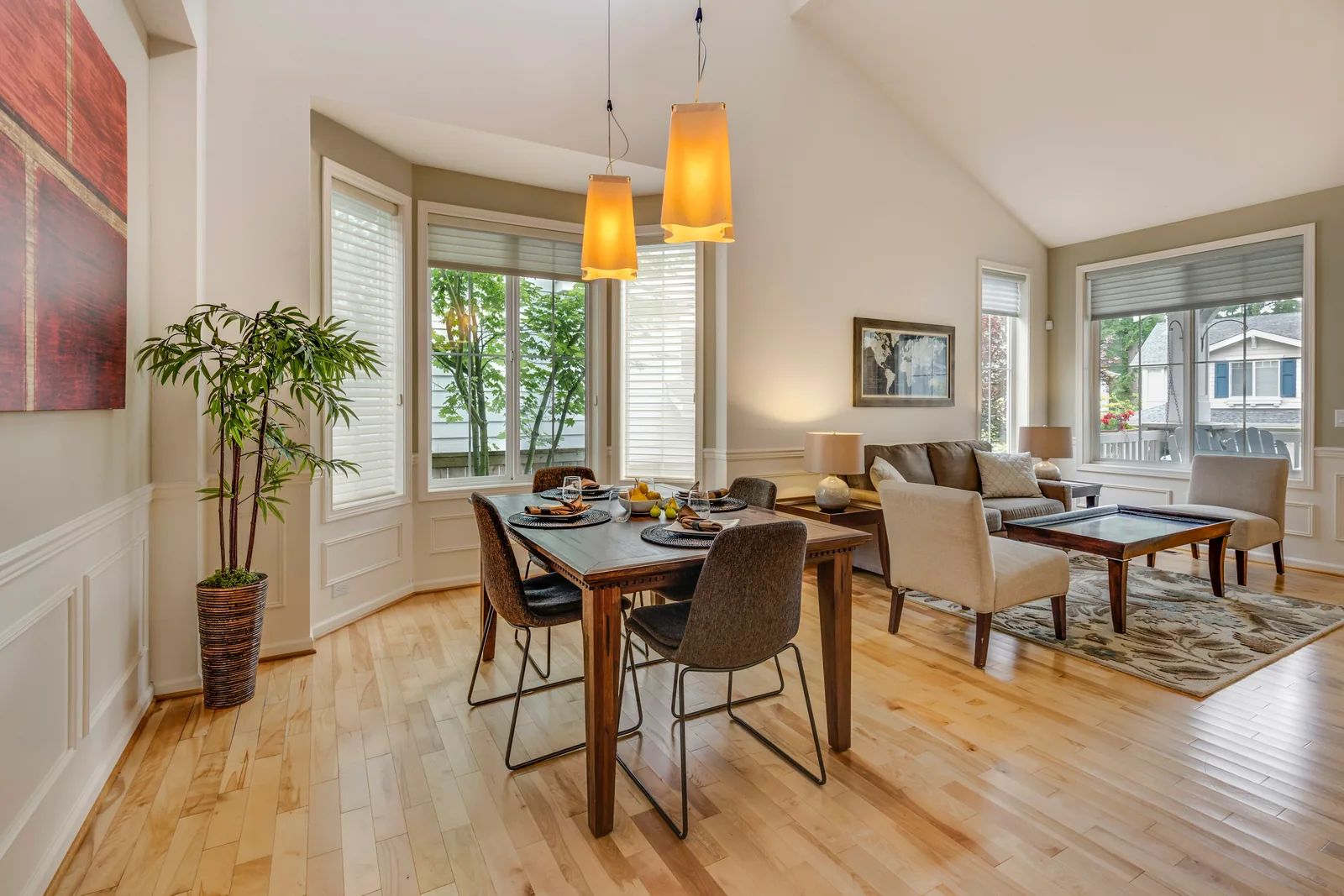 Reference photograph: a dining and living space with tall windows, timber flooring and warm pendant lights.