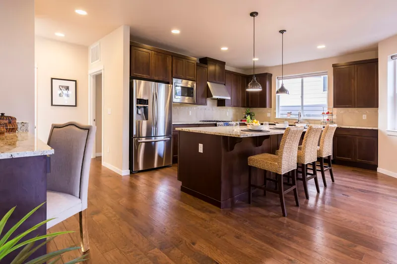 Reference photograph: a kitchen with dark wood cupboards, a pale island and woven stools.