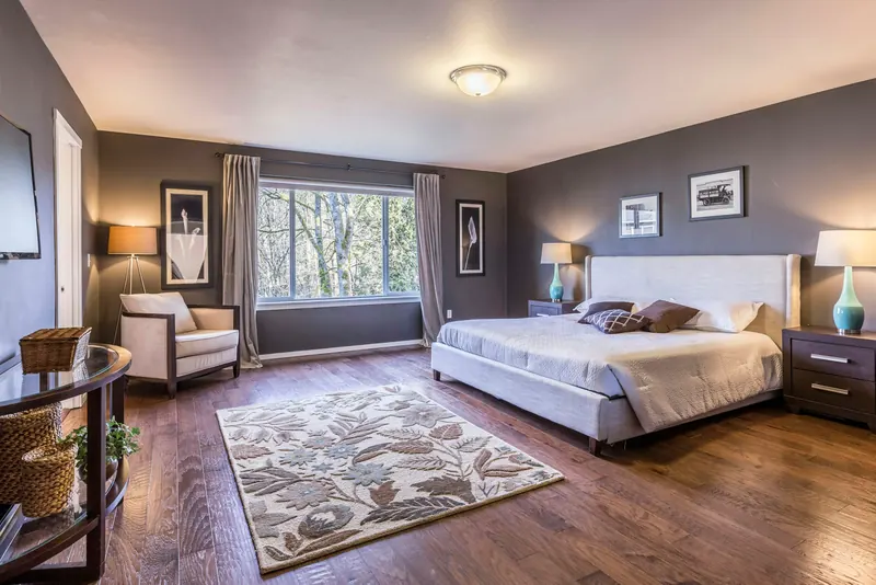 Reference photograph: a bedroom with dark walls, timber flooring and broad windows facing trees.