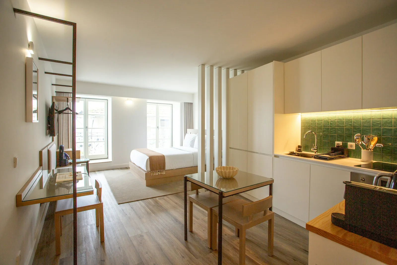 Reference photograph: a compact studio with a kitchenette, small dining table and an open sleeping zone.