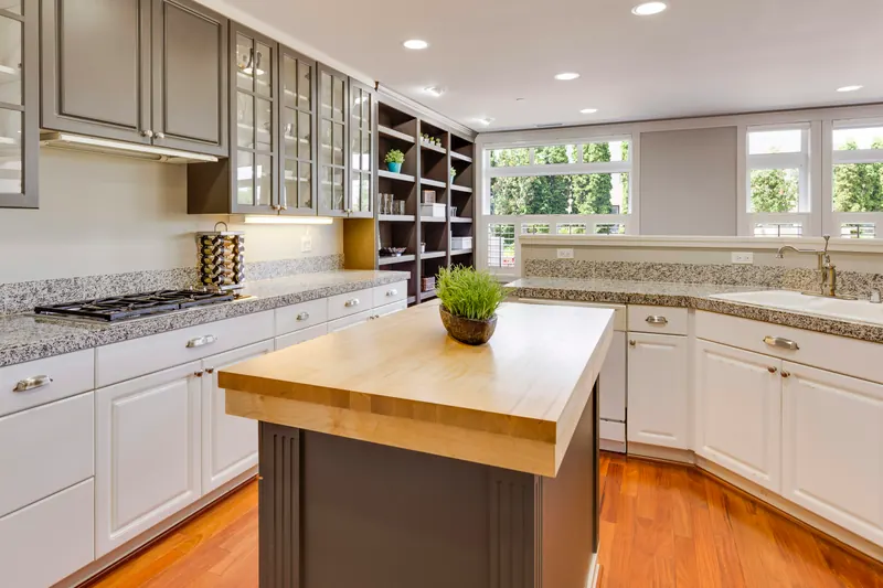 Reference photograph: a grey and white kitchen with a wood-topped island and garden-facing windows.