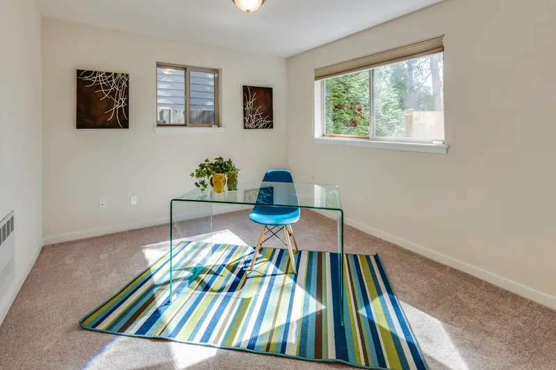 Reference photograph: a glass dining table and striped blue rug in a pale sunlit room.