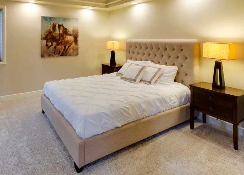 Reference photograph: a bedroom with a tufted headboard, pale bedding and warm bedside lamps.