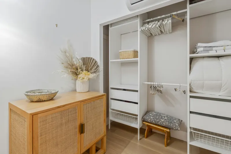 Reference photograph: open white shelving and hanging space beside a wood chest of drawers.